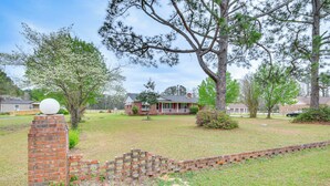 A residential area with a brick house, a lawn, and a brick wall with a spherical object on top. - Quiet & Cozy Rembert Home ~ 9 Mi to Air Force Base (Rembert)
