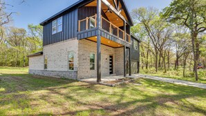 A two-story house with a balcony, brick exterior, and a large window. - Fire Pit + Grill: Lakeside Gun Barrel City Home! (Mabank)