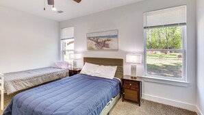 A bedroom with a single bed, a smaller bed, a ceiling fan, a window with blinds, and a painting on the wall. - Fire Pit + Grill: Lakeside Gun Barrel City Home! (Mabank)