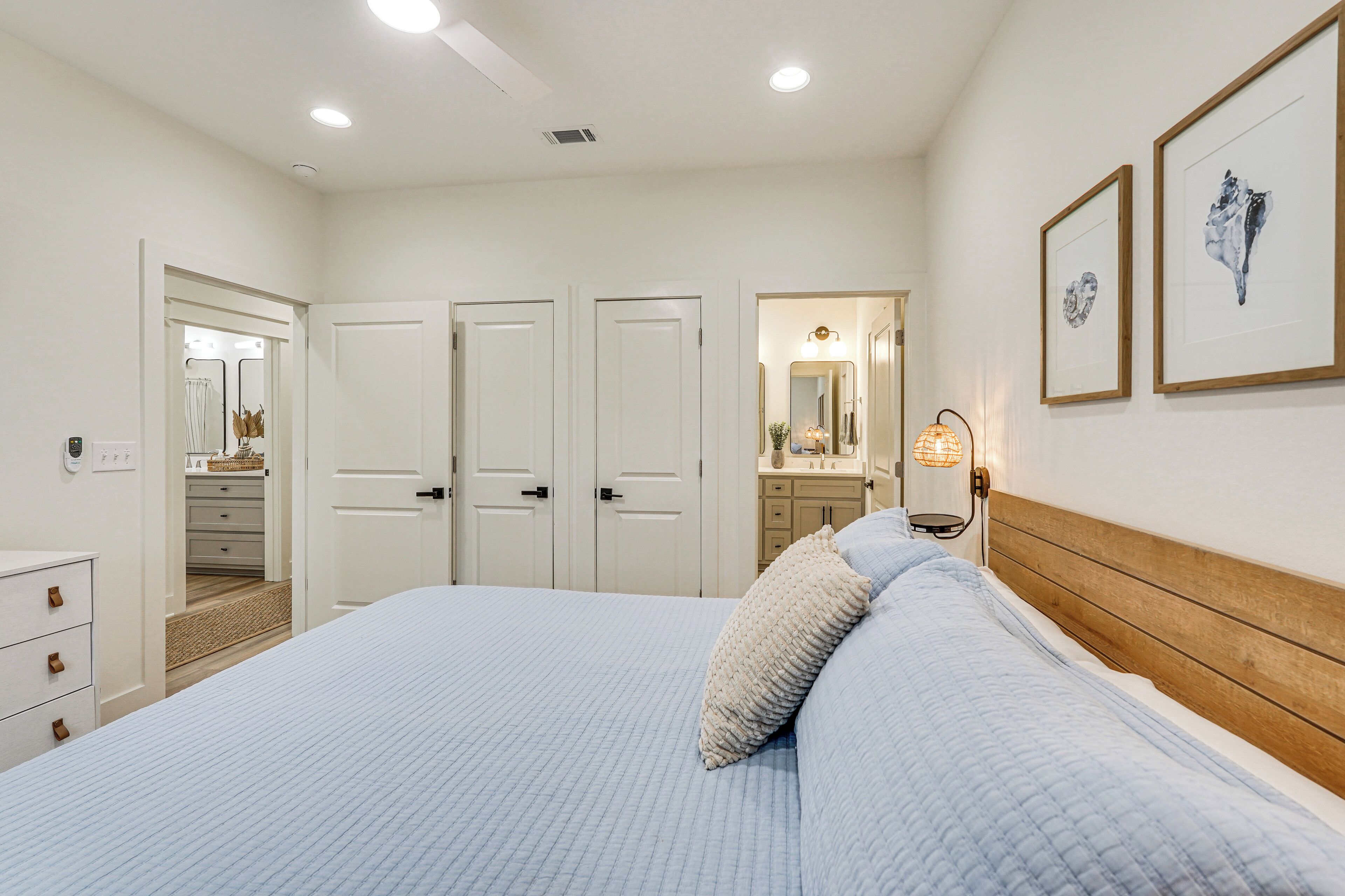 A bedroom with a large bed, a wooden headboard, a nightstand, a mirror, and framed artwork on the wall.