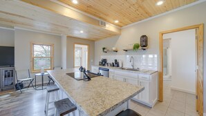 A spacious kitchen with a large island, wooden ceiling, and white cabinetry.