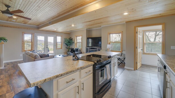 A spacious kitchen with a large island, wooden ceiling, and a built-in oven.