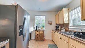 A kitchen with a stainless steel refrigerator, wooden cabinets, a window with blinds, and a coffee bar sign. - 1 Mi to Dtwn Waco! Lovely Home w/ Fire Pit Table (Waco)