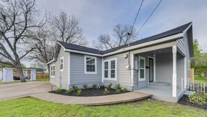 A two-story house with a covered porch, a front yard with a small garden, and a visible garage. - 1 Mi to Dtwn Waco! Lovely Home w/ Fire Pit Table (Waco)
