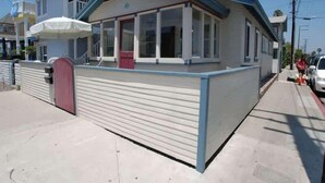 Un bâtiment à deux étages doté d’un patio couvert et d’une porte rouge.