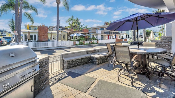 An outdoor patio with a grill, seating, and umbrellas. - 223 34th St A | Beautiful beach house, 2 blocks to the sand (Newport Beach)