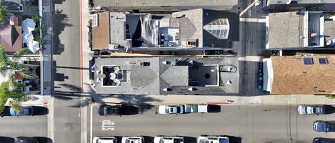 An aerial view of a parking lot with multiple cars, a stop sign, and buildings with various roof designs.