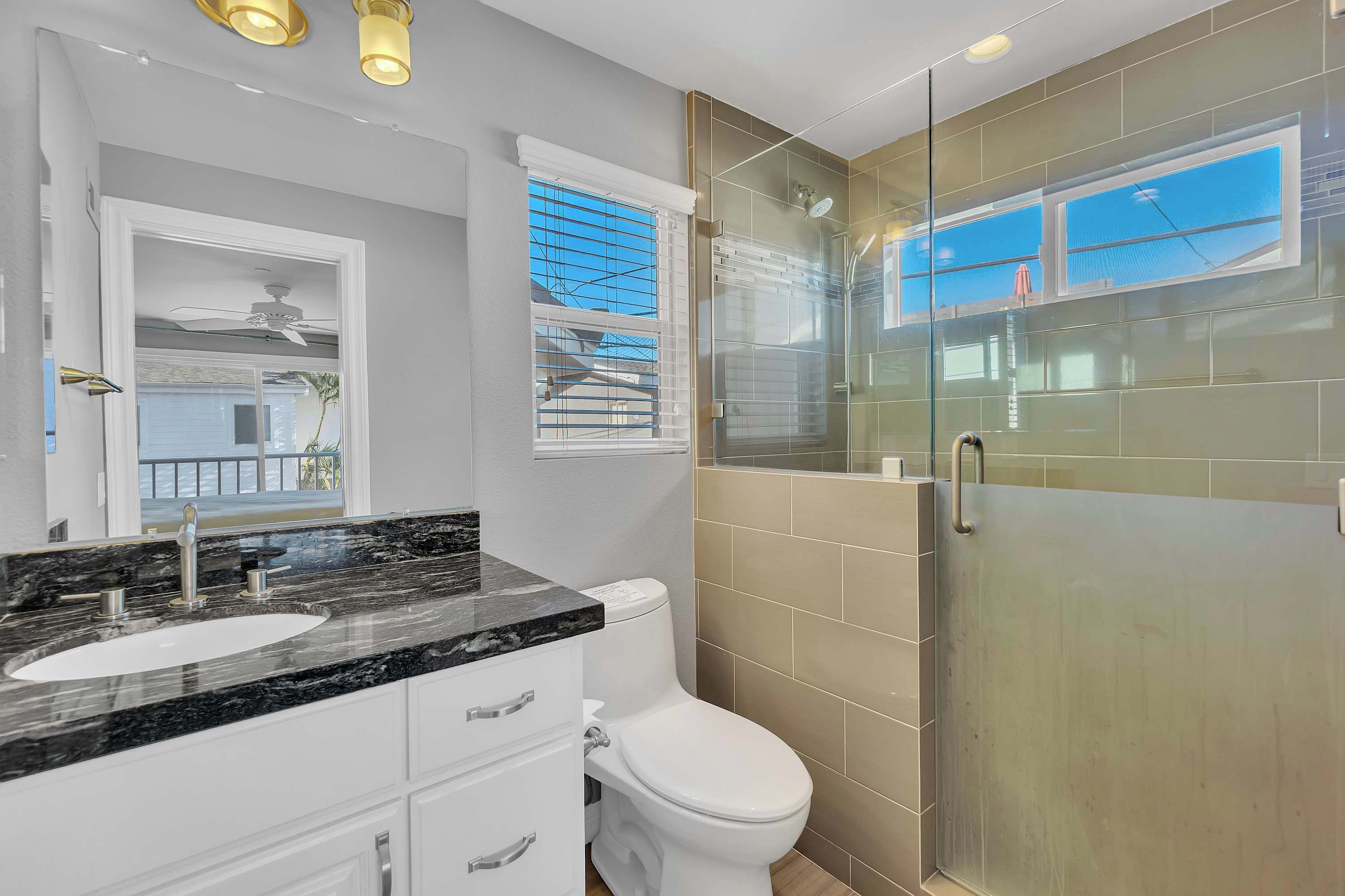 A modern bathroom with a glass-enclosed shower, a white toilet, and a marble countertop sink.