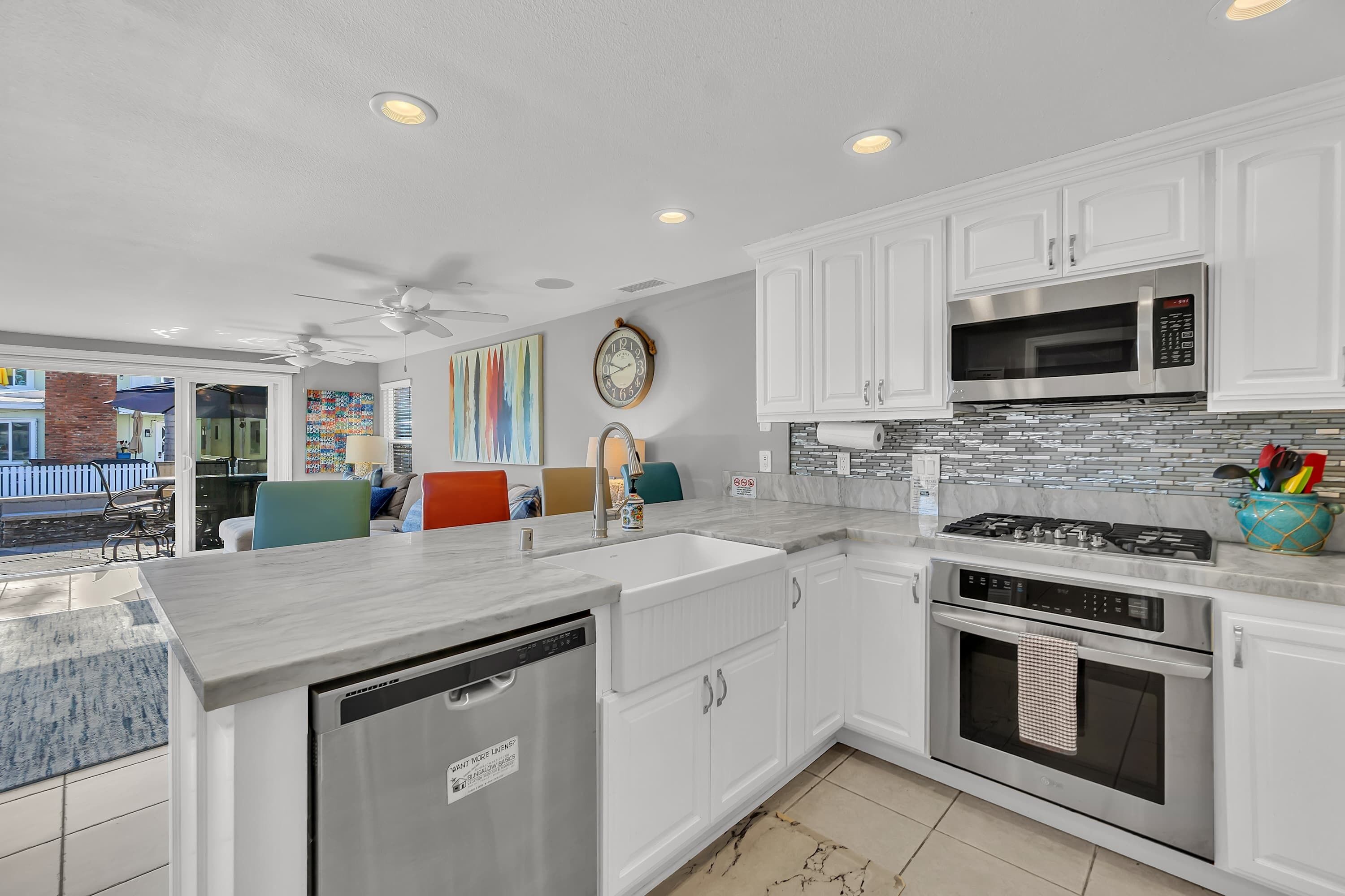 A modern kitchen with white cabinets, a stainless steel microwave, a gas stove, and a dishwasher.