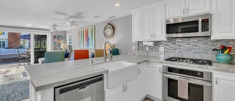 A modern kitchen with white cabinets, a stainless steel microwave, a gas stove, and a dishwasher.