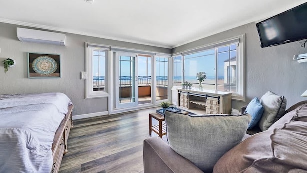 A spacious room with a large bed, a sofa, and a balcony with a view of the sea.