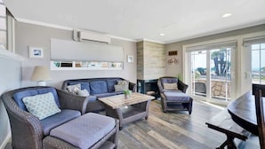 A modern living room with wicker furniture, a fireplace, and a large sliding glass door leading to an outdoor area.