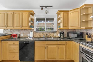 A kitchen with wooden cabinets, a black dishwasher, a microwave, and a coffee maker.