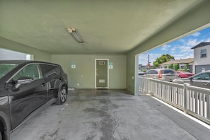 A parking garage with a car parked inside, a door labeled 'RESERVED PARKING A', and a sign indicating 'RESERVED PARKING B'. - Lower Unit, Close to Restaurants, and Shopping (Newport Beach)