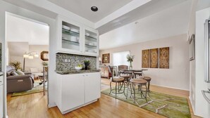 Uma cozinha moderna com armários brancos, bancada de granito e um espaço de refeições com mesa e cadeiras.