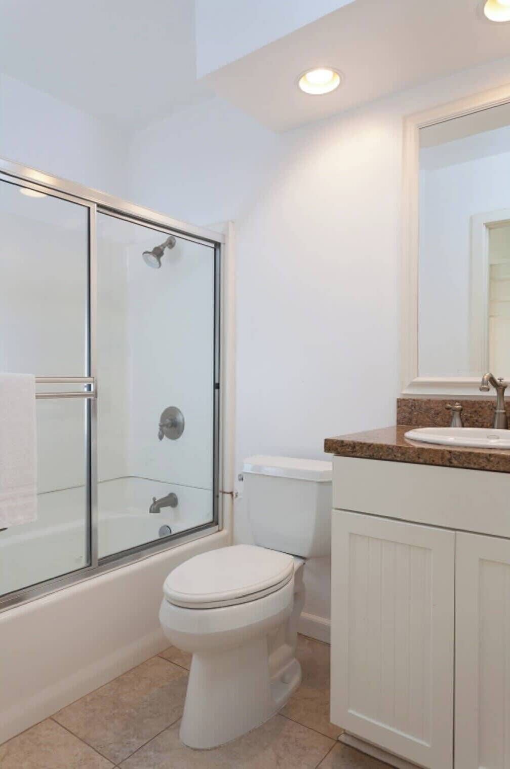 Une salle de bain avec une douche à parois de verre, des toilettes et un meuble-lavabo avec un évier et un miroir.