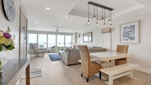 Uma sala de estar ampla com uma mesa de jantar, cadeiras de vime e um banco.