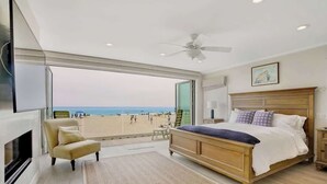 Quarto com uma janela grande, cama, poltrona e ventoinha de teto.