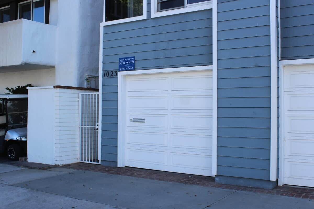 A two-story building with a garage door and a sign indicating vacation rental availability.