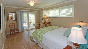 A bedroom with a bed, a chair, a desk, a lamp, and a ceiling fan. - 1009 W Bay | Quaint Cottage Steps to Sand (Newport Beach)