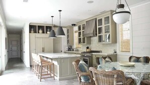 A kitchen with a central island, bar stools, and a dining table with chairs. - 1028 W Oceanfront | Beautiful 5bdr Beachfront on Scenic Bike Path (Newport Beach)