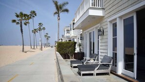 A beachfront property with a patio area featuring lounge chairs and a small table. - 1028 W Oceanfront | Beautiful 5bdr Beachfront on Scenic Bike Path (Newport Beach)