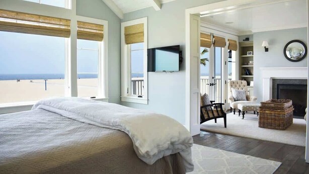 A bedroom with a large bed, a TV, and a view of the beach. - 1028 W Oceanfront | Beautiful 5bdr Beachfront on Scenic Bike Path (Newport Beach)