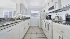 A modern kitchen with white cabinetry, granite countertops, a built-in oven, and a microwave. - 1404 W Oceanfront A | Value Beachfront w/Large Patio On The Bike Path (Newport Beach)