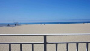 Een strand met een heldere lucht, een zandstrand en enkele mensen in de verte.