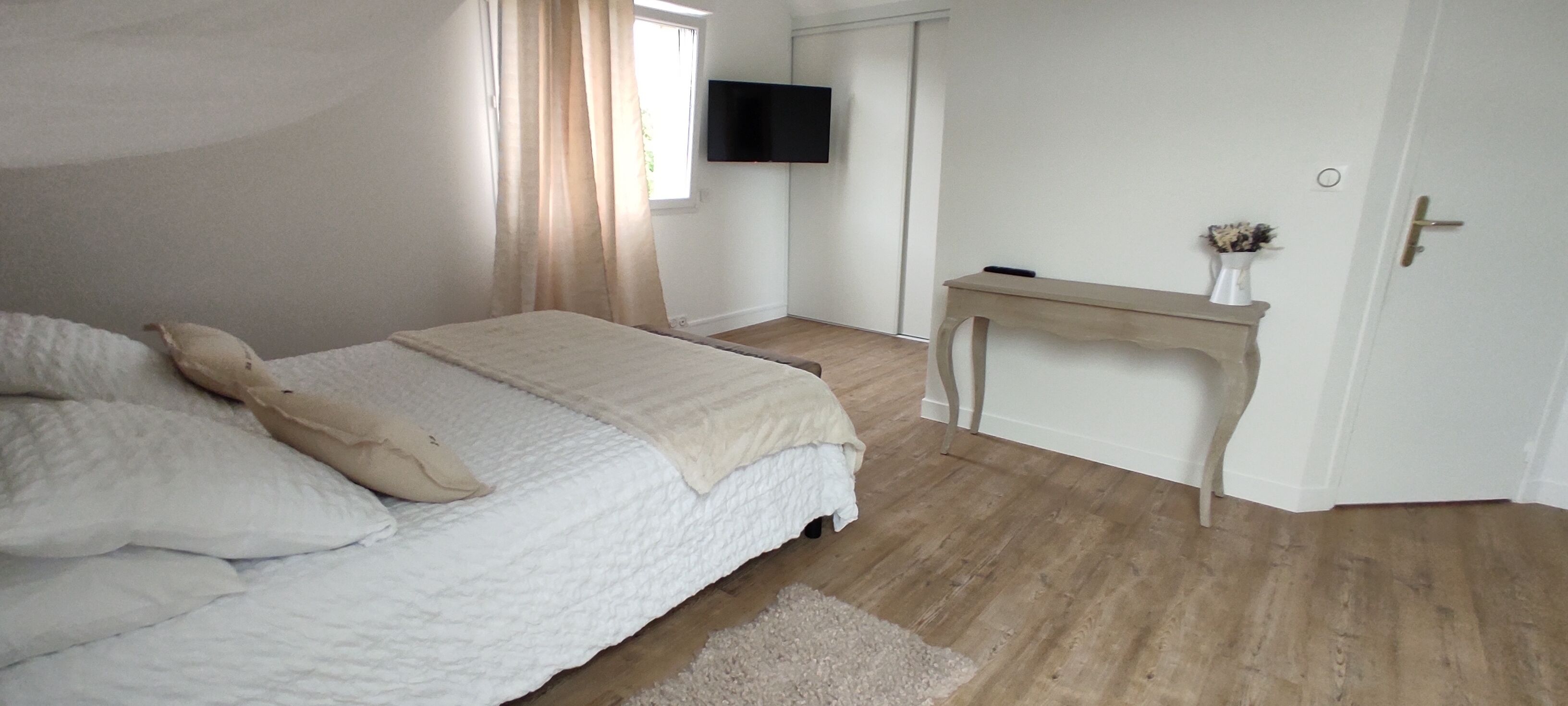 Un dormitorio con cama, escritorio, televisión y puerta.