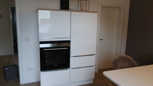 A compact kitchen with a built-in oven and a white refrigerator.
