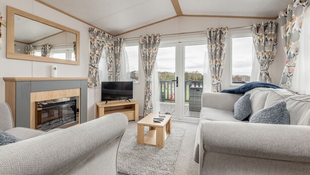 A living room with a fireplace, a television, and a sofa. - Lodge No 10 | St Andrews Lodge Park (Strathkinness)