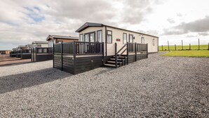 A single-story mobile home with a front porch and a gravel driveway. - Lodge No 10 | St Andrews Lodge Park (Strathkinness)