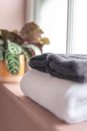 A folded towel on a shelf next to a potted plant. - House Arundel (Arundel)