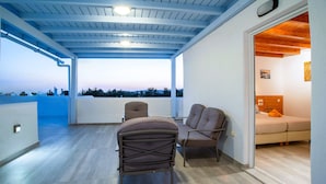 Uma área de estar coberta ao ar livre com vista para a paisagem, uma cama e teto de madeira.