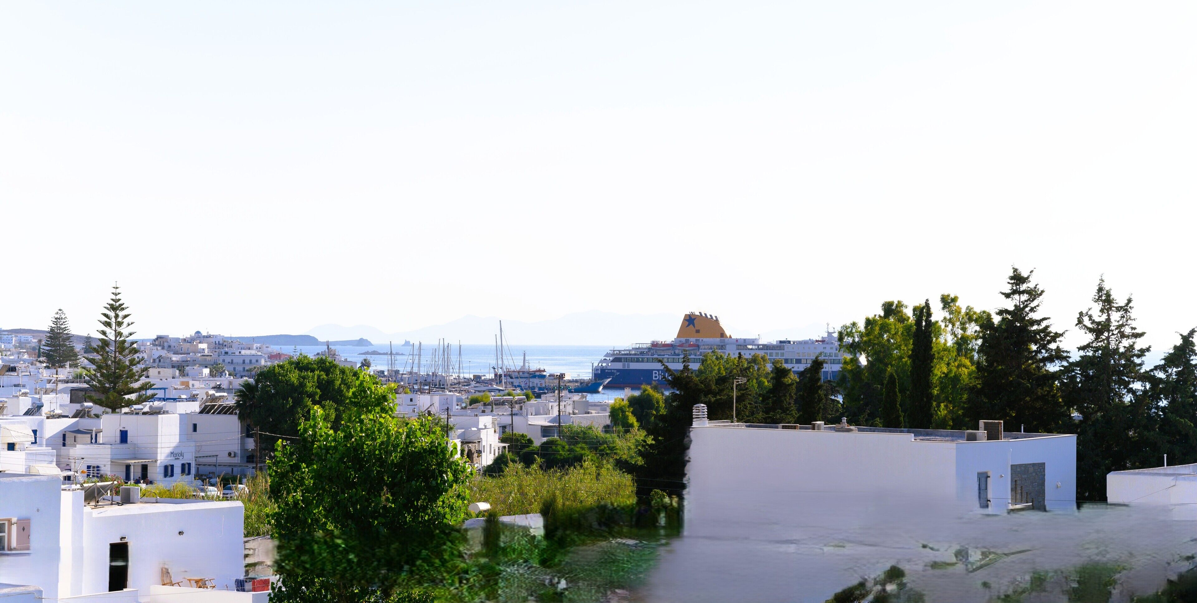 A coastal town with white buildings, a cruise ship, and a clear view of the sea.