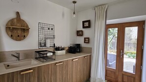 Et køkken med træskabe, en vask, kaffemaskine og en hængende lampe.