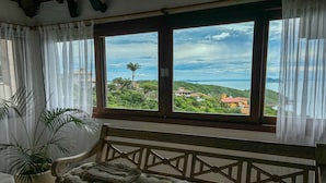Una habitación con un ventanal grande, un banco acolchado y una planta en maceta.
