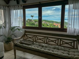 Una habitación con un ventanal grande, un banco acolchado y una planta en maceta.