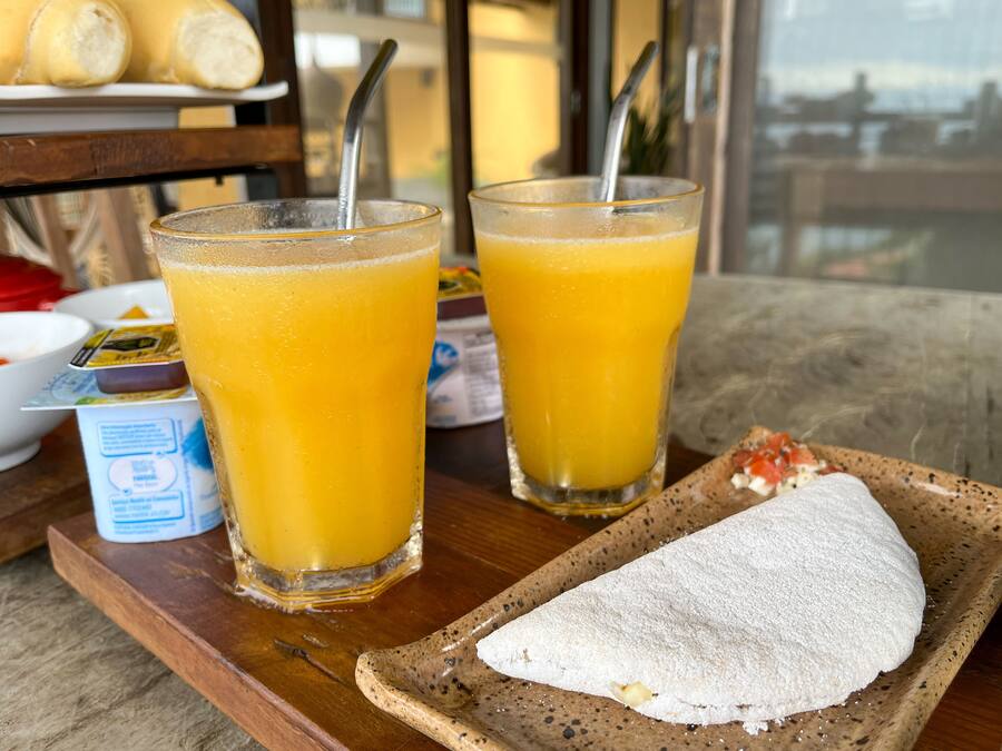 Dos vasos de jugo de naranja sobre una bandeja de madera con un pastel.