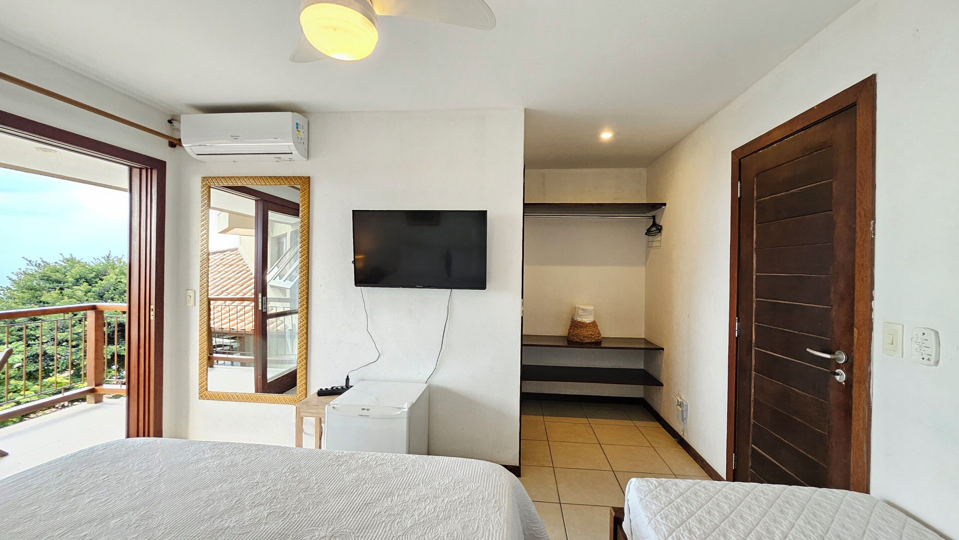 Una camera d'albergo con due letti, una TV fissata al muro, un balcone con vista e una scala che conduce a un piano superiore.