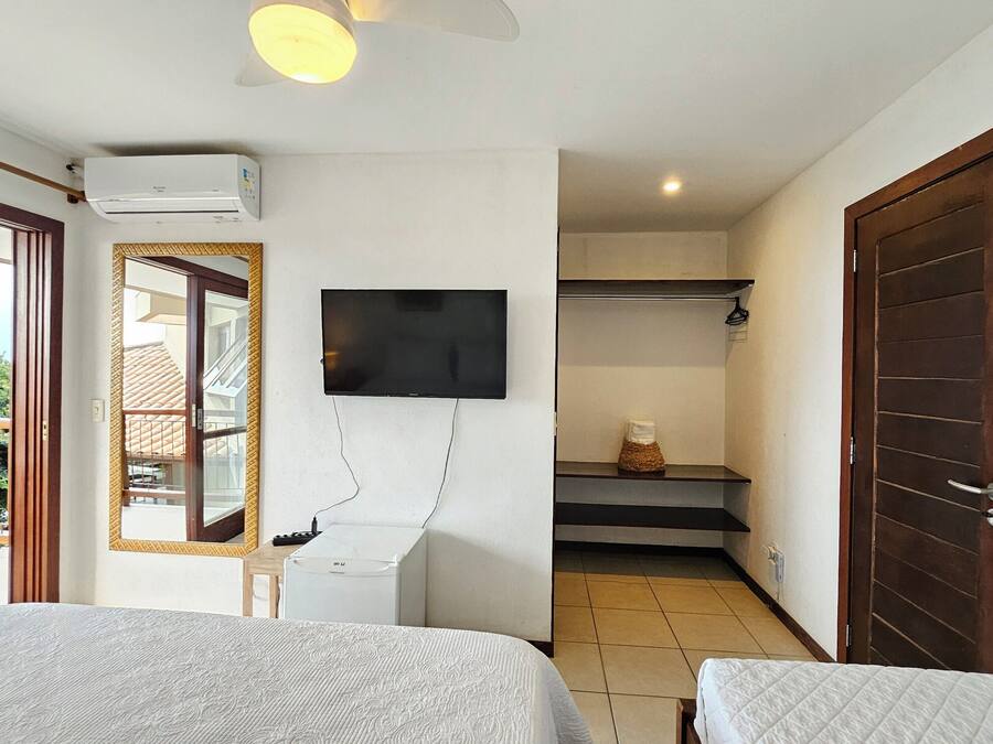 Una camera d'albergo con due letti, una TV fissata al muro, un balcone con vista e una scala che conduce a un piano superiore.
