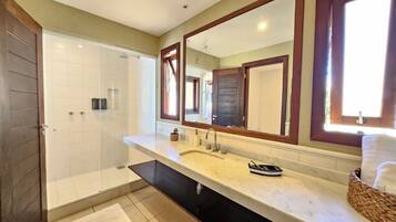 Un baño con ducha, lavamanos, espejo y ventana.