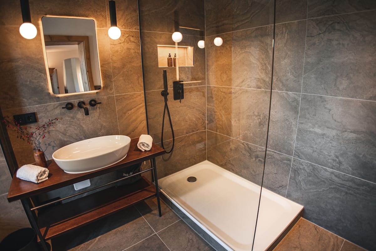 Un baño moderno con un lavamanos grande, un espejo y una ducha a ras de suelo.