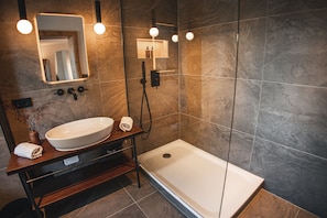A modern bathroom with a large sink, a mirror, and a walk-in shower. - Suiten Zantl (Bad Toelz)