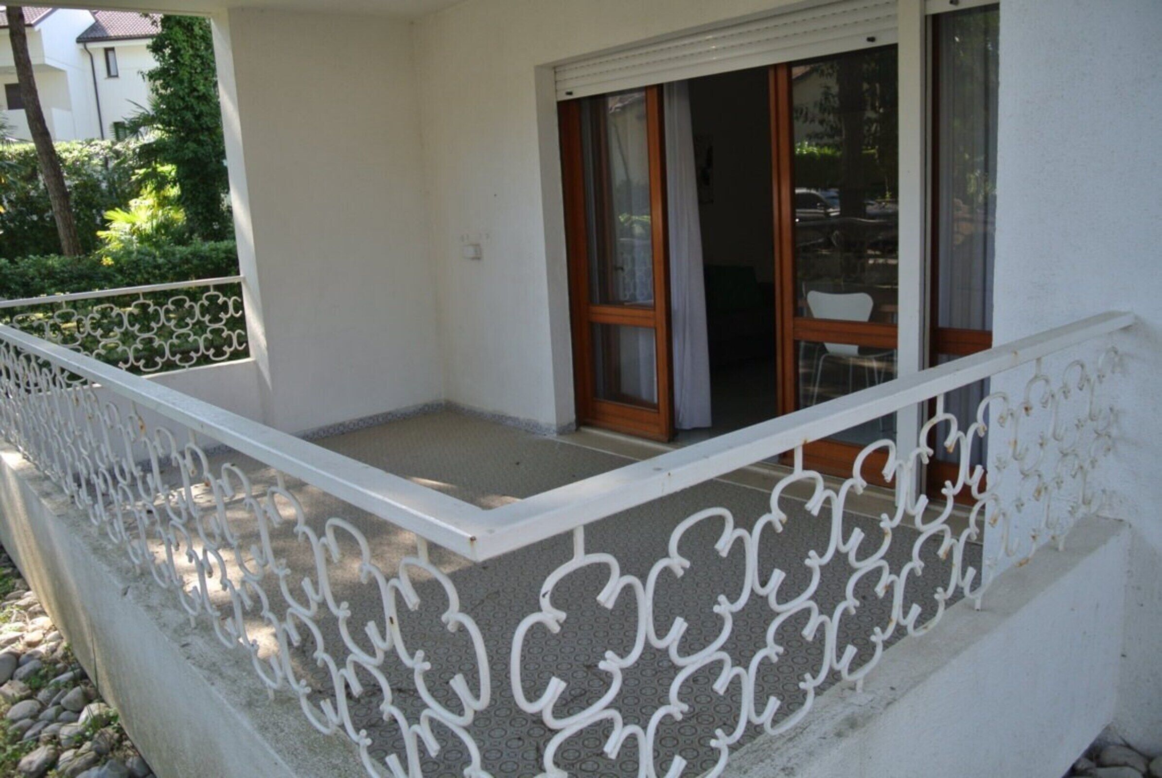 A balcony with a white metal railing, a window with a wooden frame, and a door with glass panels.