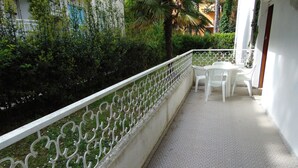 Ein Balkon mit weißer Reling, einem kleinen Tisch und Stühlen.