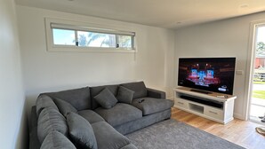 Una sala de estar moderna con un sofá modular, un televisor de pantalla plana y un ventanal.