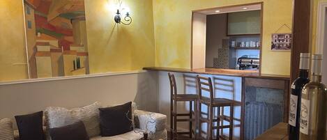 A cozy living area with a sofa, chairs, a small table, and a bar area with a mirror and kitchen items.
