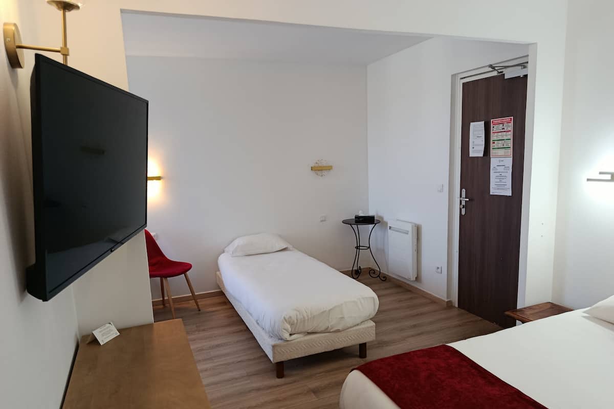 Une chambre d’hôtel comprenant un lit, un bureau avec une chaise, une télévision, une petite table et une porte avec une pancarte.